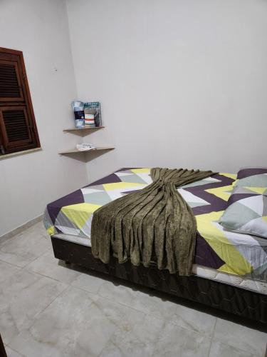 a bed with a blanket on it in a room at Casa por do sol Flecheiras in Flecheiras