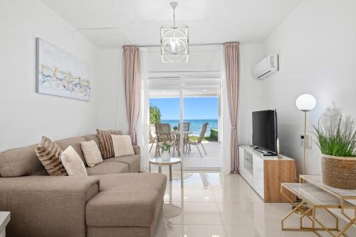 a living room with a couch and a tv at Wavestone Beachfront House in Meneou