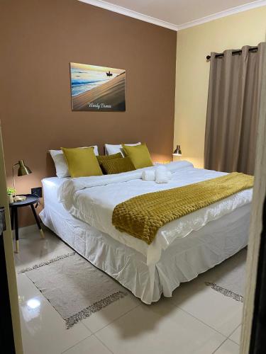 a bedroom with a large white bed with yellow pillows at Windy Dunes Self -Catering Accommodation, Luderitz in Lüderitz