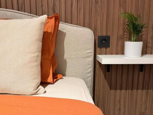 a bed with an orange pillow and a plant on a shelf at Residentie Peter Pan in Knokke-Heist