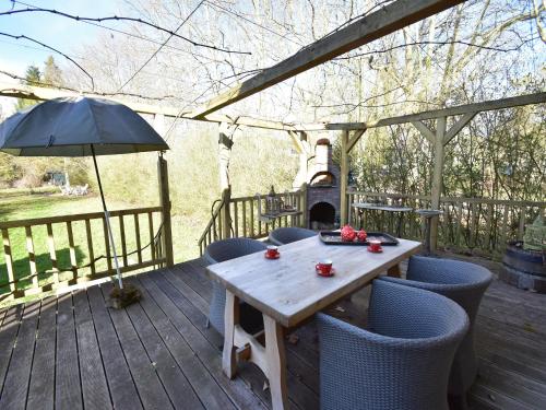 een houten tafel met stoelen en een parasol op een terras bij Cottage in France with Garden near Lake in Montaron