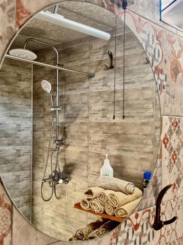 a round mirror in a bathroom with a shower at Megruli House in Poti