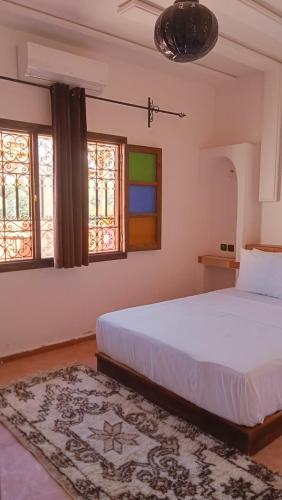a bedroom with a large white bed and windows at Riad La Belle Vue in Boumalne