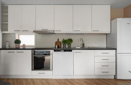 une cuisine blanche avec des armoires blanches et un réfrigérateur dans l'établissement Cozy apartment on tomasjordnes, à Tomasjorda