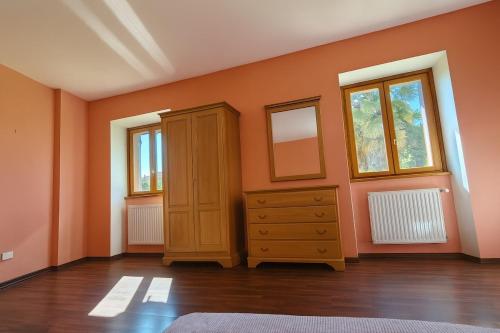 AmenoにあるHome and garden nestled in Amenoのキャビネットと2つの窓があるオレンジ色の部屋