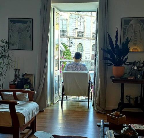 a man sitting in a chair looking out of a door at Marina Lounge Home in Ponta Delgada
