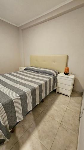 ein Schlafzimmer mit einem Bett mit einer gestreiften Decke in der Unterkunft Edificio-Pellegrini PB in Bragado