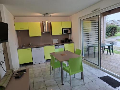 eine Küche mit limettengrünen Schränken und einem Tisch und Stühlen in der Unterkunft Cottage Le Vau 2, draps fournis, piscine in Chaveignes