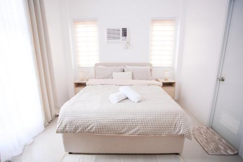 a white bedroom with a bed with two towels on it at Casa de Amor Modern Comfort across the pool in Dauis