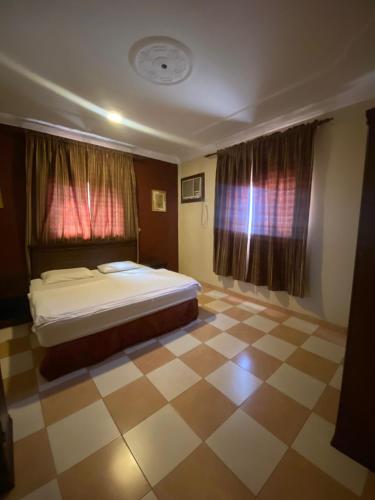 a bedroom with a bed and a checkered floor at أللورا زون - Alora Zone in Abha