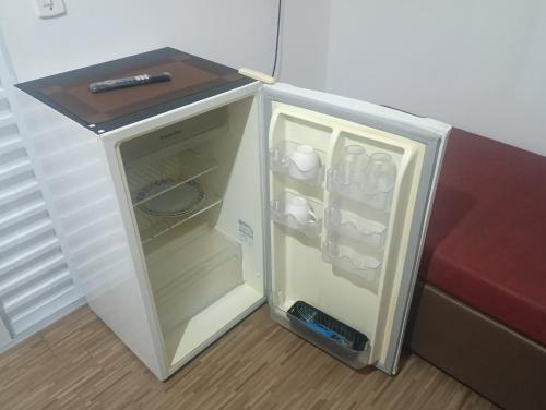 ベルチオガにあるSuíte Independente - Praia Indaiá e Riviera - MarDoceLar Bertiogaのソファの横にドアが開いたままの小型冷蔵庫