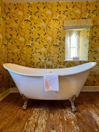 a bath tub in a bathroom with a yellow wall at The Seagrave Arms in Weston Subedge