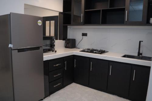 a kitchen with black cabinets and a stainless steel refrigerator at Cinnamon Wave Villa - Thalaramba, Mirissa in Matara