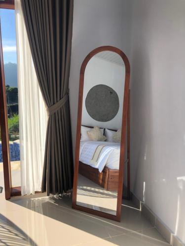 a mirror in a room with a bed and a window at Skyland Kintamani in Kubupenlokan