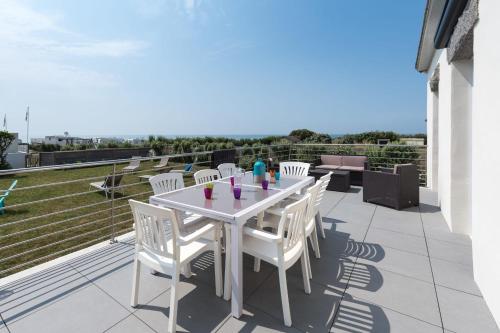 a white table and white chairs on a balcony at Tipoz'immo-Maison de la Baie vue mer accès à pied - jardin clos in Penhors