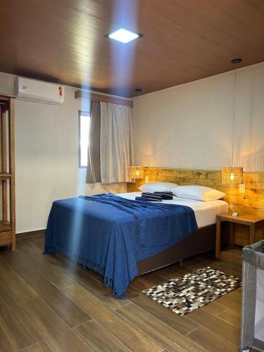 a bedroom with a large bed with a blue blanket at Casamares Ipioca Beach Hibiscus Maceió in Maceió