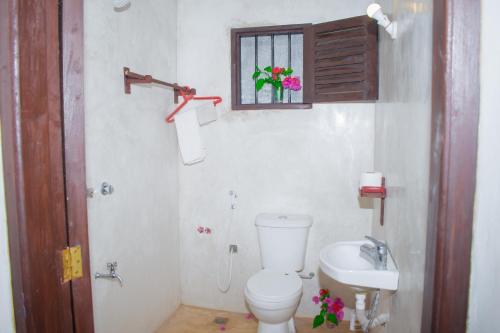 a bathroom with a toilet and a sink and a window at Amani Guest House Lamu in Lamu