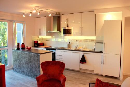 a kitchen with white cabinets and a red chair at Fun and quiet in Paris