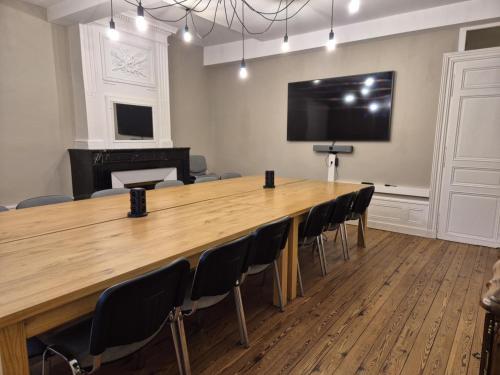 ein großer Konferenzraum mit einem großen Holztisch und Stühlen in der Unterkunft Grand Gîte au cœur du village avec jardin in Regny