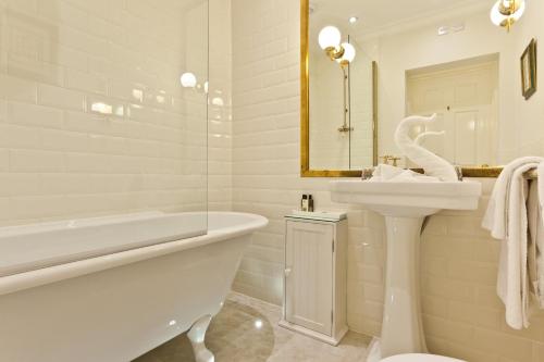 a white bathroom with a tub and a sink and a bath tub at Bridge Hotel in Buttermere