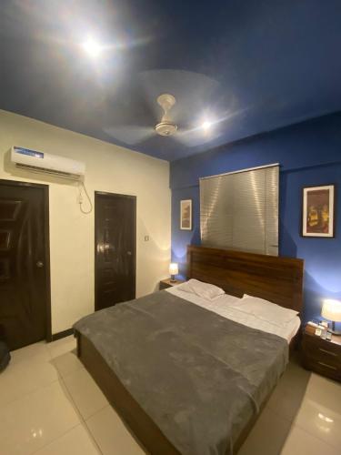 ein Schlafzimmer mit einem Bett mit einer blauen Wand in der Unterkunft Beach Side Studio Apartment in Karatschi