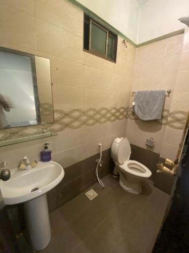 ein Badezimmer mit Waschbecken, Toilette und Spiegel in der Unterkunft Beach Side Studio Apartment in Karatschi