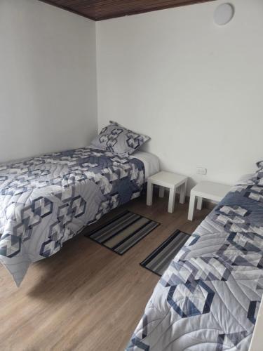 Un dormitorio con dos camas y suelo de madera. en Los Muiscas Tunja, en Tunja