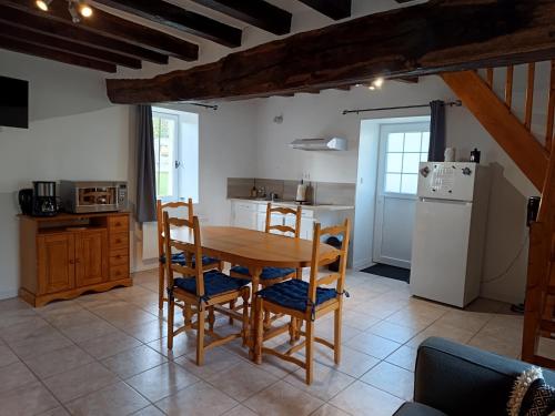 eine Küche mit Tisch und Stühlen und einem Kühlschrank in der Unterkunft Chez Elise et Margot in Saint-Cosme-en-Vairais