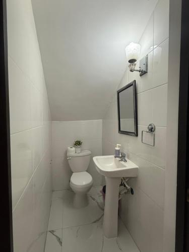 a white bathroom with a toilet and a sink at Playa Dorada Mountainview Villa in San Felipe de Puerto Plata