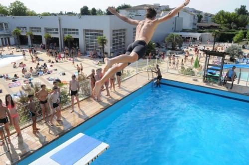 Ein Mann springt aus einem Schwimmbecken in der Unterkunft Appartement spacieux et lumineux, idéalement situé in Pessac