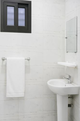 a white bathroom with a sink and a mirror at Au cœur de Angré la djibi in Cocody