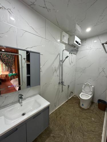a white bathroom with a sink and a toilet at Cát Lý Camping in Ha Giang