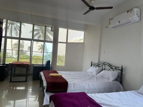 a bedroom with two beds and a ceiling fan at water front guest house in Arambol