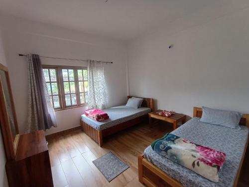 a bedroom with two beds and a window at Drukinn gaireykhet homestay in Thode
