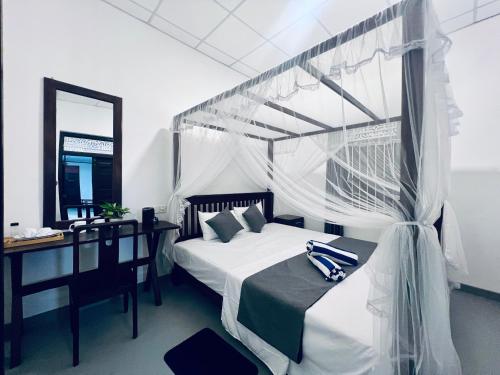a bedroom with a bed and a desk and a mirror at Villa Eco Stay in Tangalle