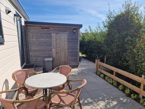 a patio with a table and chairs and a shed at Zeester in Ameland