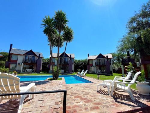 a house with a swimming pool and some white chairs at Cabañas Ayres del Lago in Potrero de los Funes