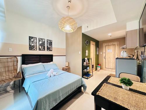 Cozy Studio Unit - Inspiria Condominium Beside Abreeza Mall في مدينة دافاو: غرفة نوم بسرير ازرق ومطبخ