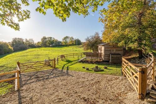 un granero con una cerca de madera junto a un campo en The Cosy Goose, en Charlton