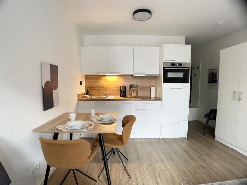 a kitchen with white cabinets and a table and chairs at Design Vogue Apartment-Zentral-WiFi-4Personen in Metzingen