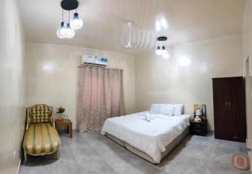 a bedroom with a bed and a chair and lights at Patio Boy Dean Guesthouse in Fujairah