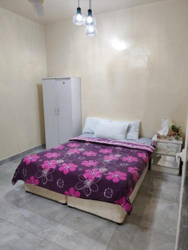 a bedroom with a bed with a purple blanket at Patio Boy Dean Guesthouse in Fujairah
