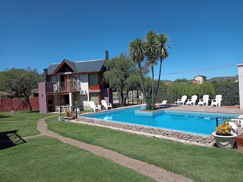 a house with a swimming pool in front of a house at Cabañas Ayres del Lago in Potrero de los Funes