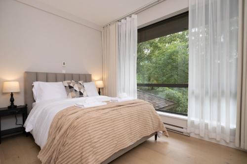 Un dormitorio con una cama y una ventana grande en Stylish Scenic Oasis 2-Bedroom Suite West Van, en West Vancouver