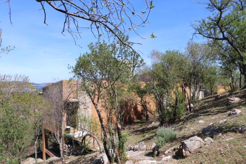 a hillside with trees and rocks on a sunny day at Refugio de las nubes in Las Rabonas
