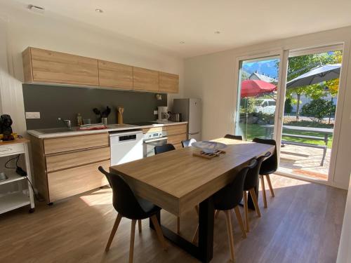 eine Küche mit einem Holztisch und Stühlen sowie eine Küche mit einem Fenster in der Unterkunft CHALET LAC BLEU Luchon proche Thermes 3ch terrasse bbq pkg 7p in Saint-Mamet