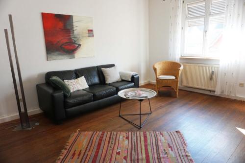 un salon avec un canapé noir et une table dans l'établissement Gemütliche Künstlerwohnung mit großer Dachterrasse, à Weinheim