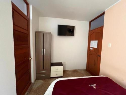 una camera da letto con un letto e una TV a parete di Casona Tupac Hotel Cusco a Cuzco