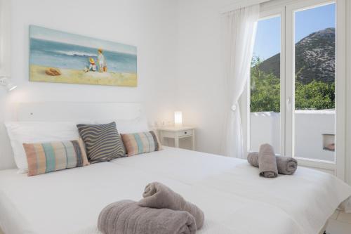 a white bedroom with a bed and a window at Sunny Villa Sifnos in Apollonia