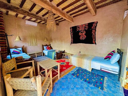 a room with two beds and a table and chairs at La Petite Kasbah in Zagora